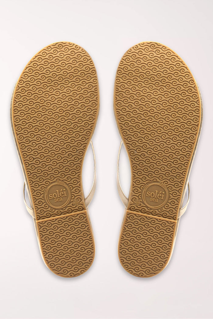 Pair of champagne gold flip-flops on a white background