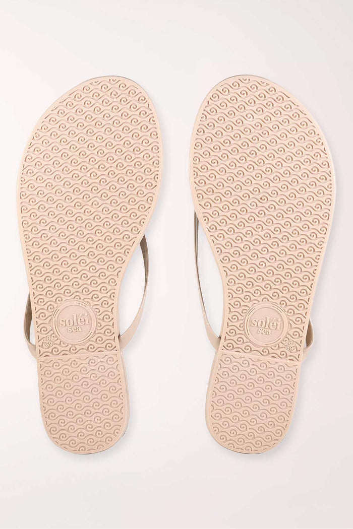 Pair of beige flip-flops on a white background