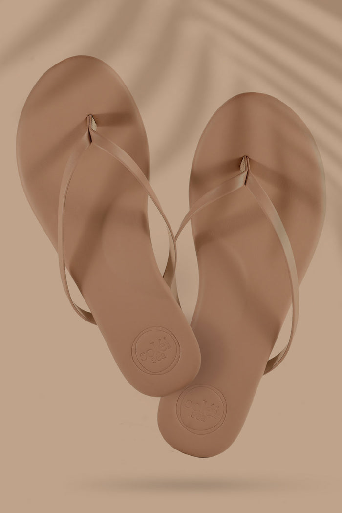Pair of brown flip-flops on a beige background