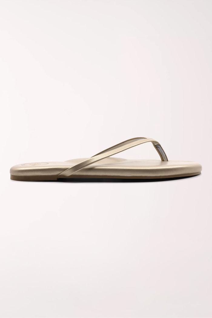 Pair of champagne gold flip-flops on a white background