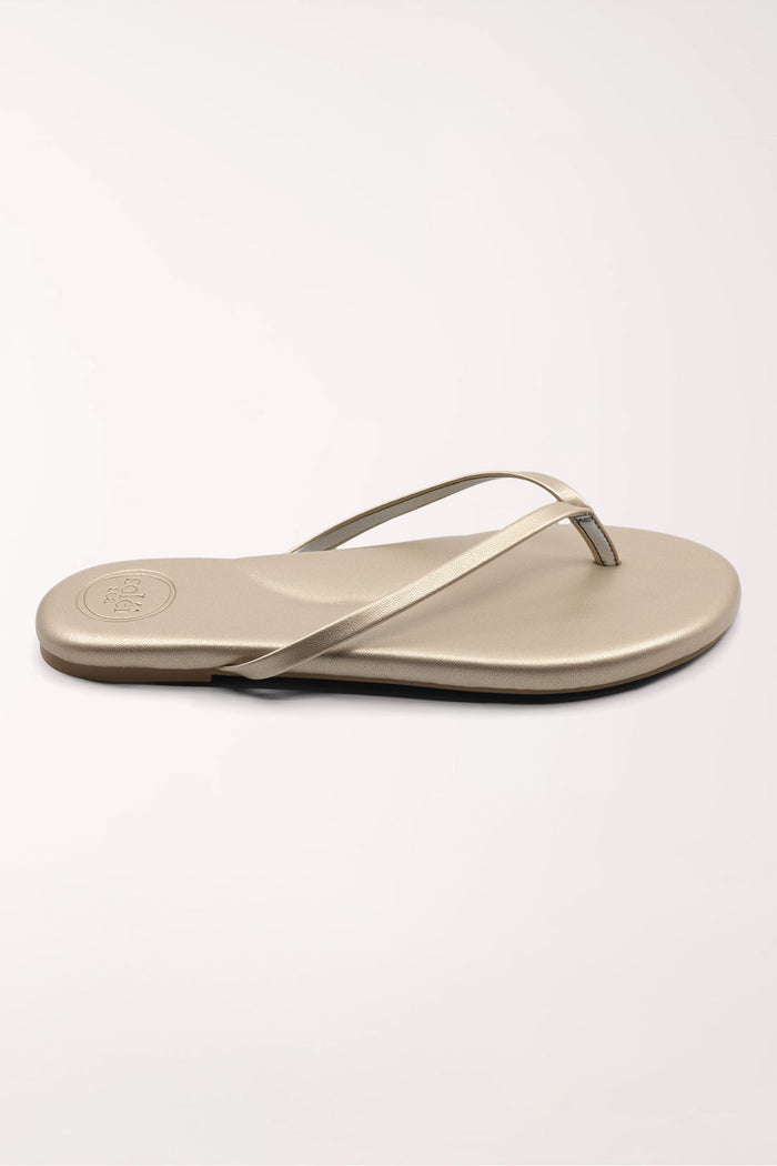 Pair of champagne gold flip-flops on a white background