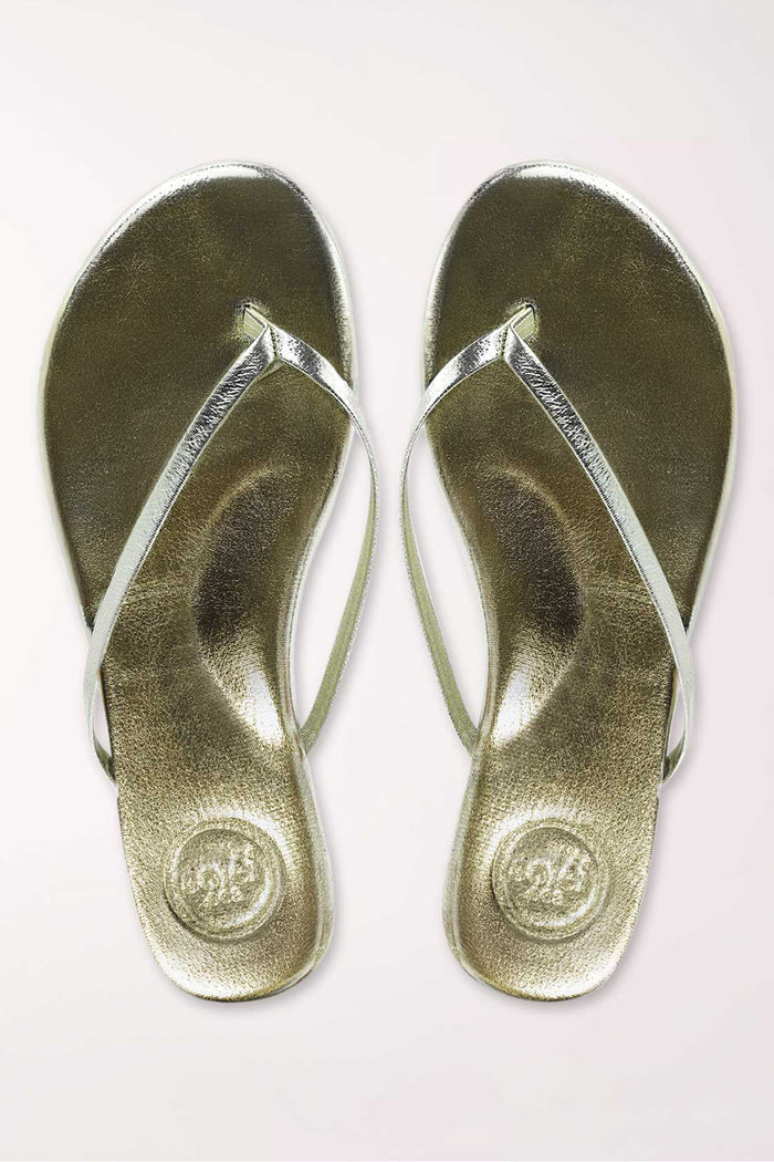Pair of gold metallic sandals on a white background