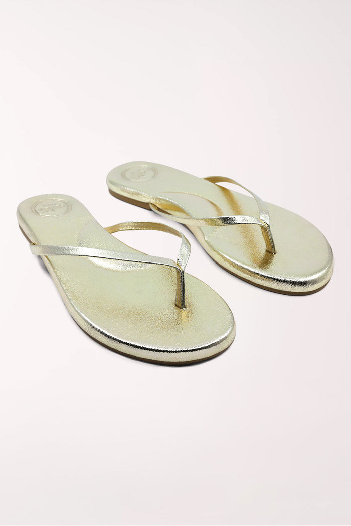 Pair of gold metallic sandals on a white background