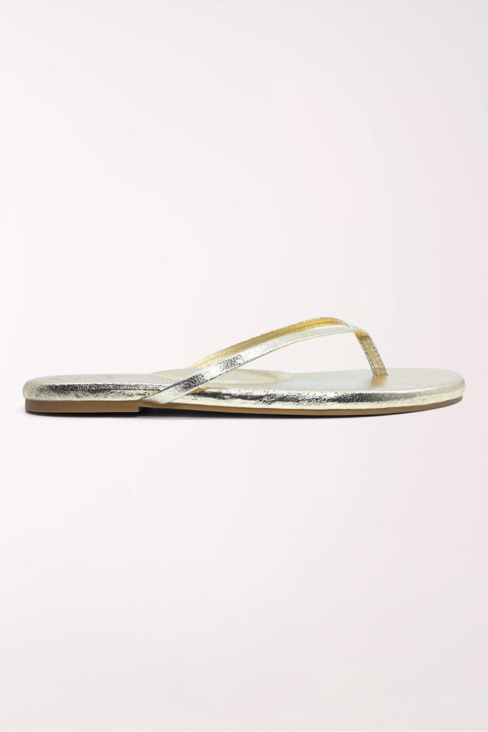 Pair of gold metallic sandals on a white background