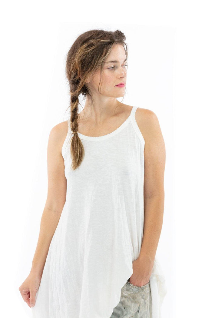 Woman in Magnolia Pearl artisan white dress with whimsical vintage style, braided hair