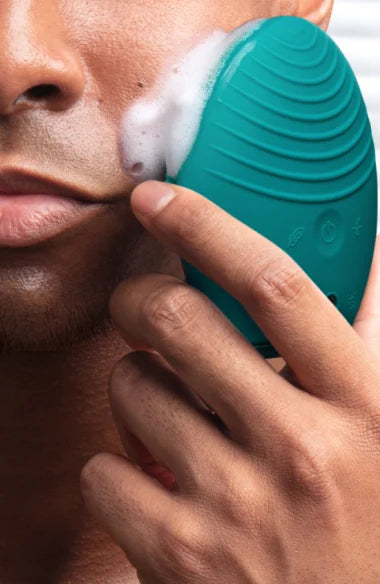Close-up of a man using the LUNA™ 4 MEN | FOREO facial cleansing device with foam on his cheek, demonstrating skincare for men.