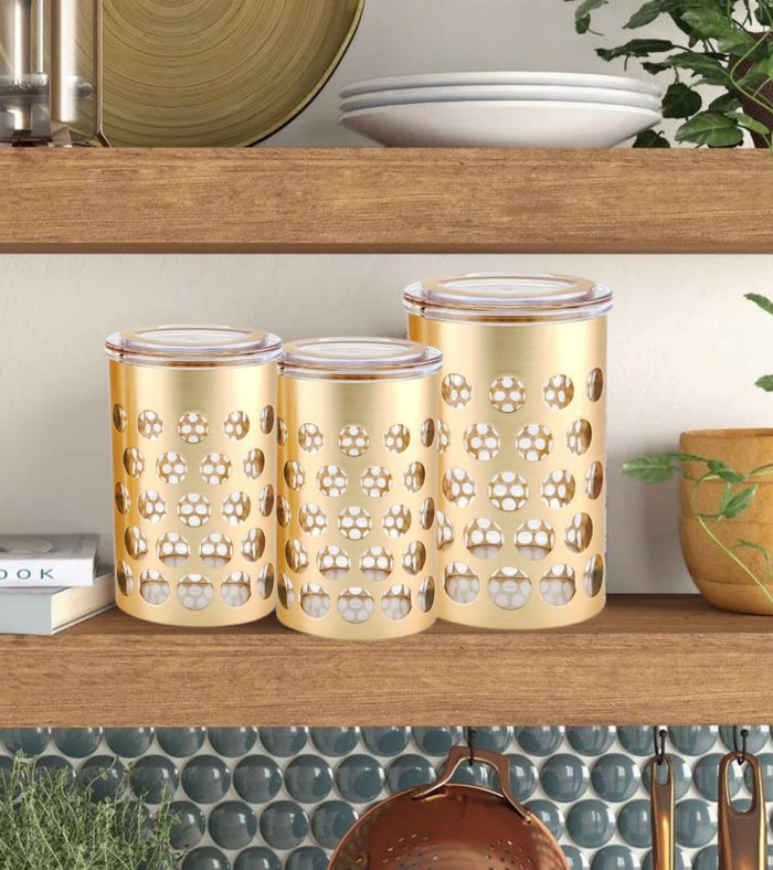 Set of three gold airtight storage jars with clear lids and round polka dot pattern.
