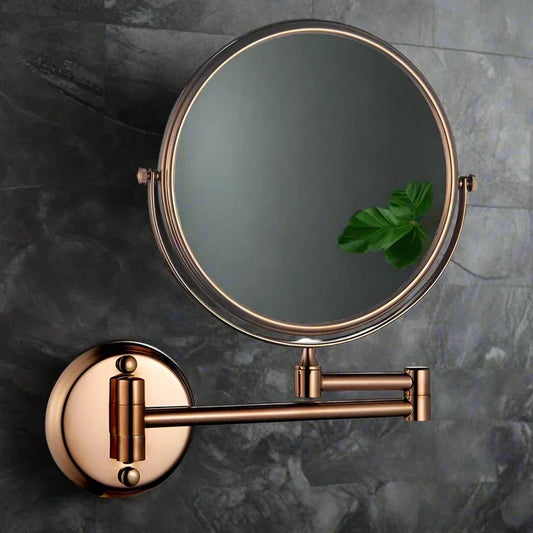 Round 3x magnification shaving mirror with rose gold rim and adjustable pivot arms on dark grey marble - Glazonoid