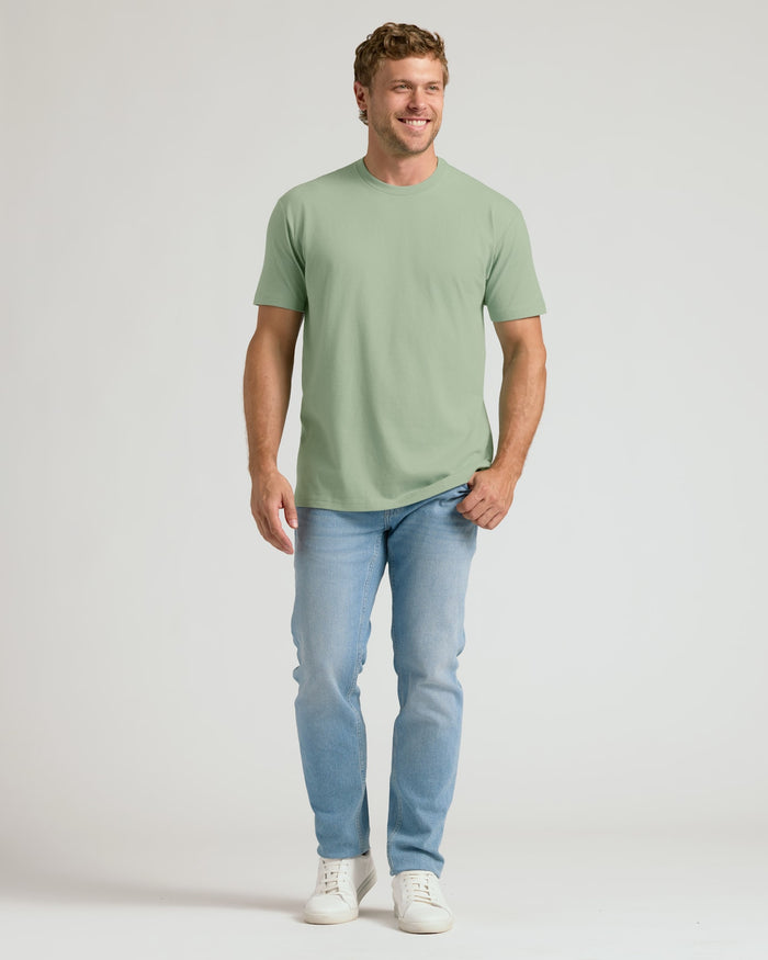 Man wearing a green t-shirt and light blue jeans on a white background