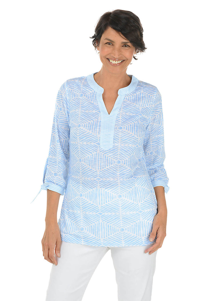 Woman wearing a light blue patterned shirt on a white background.