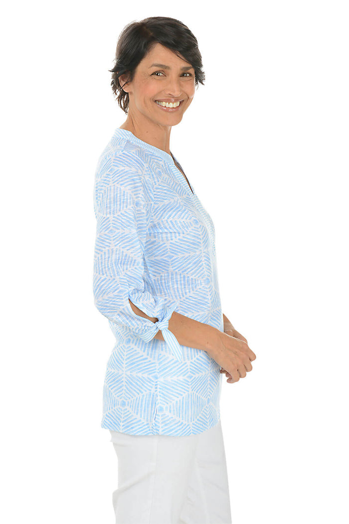 Woman wearing a light blue patterned shirt on a white background. Side shot.