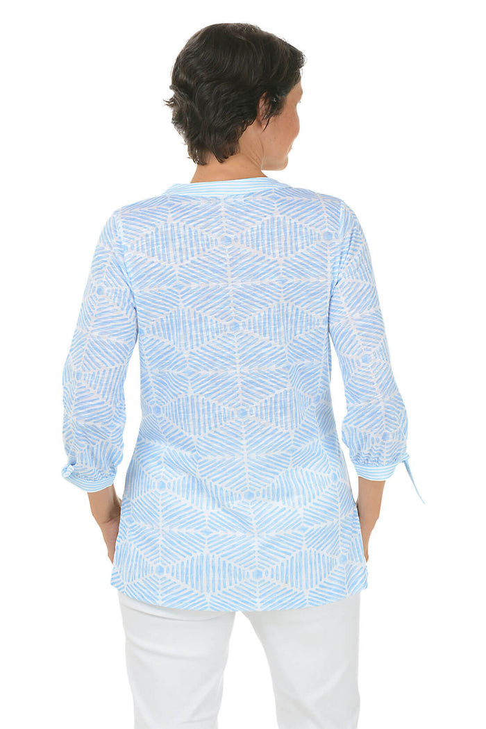 Woman wearing a light blue patterned shirt on a white background. Back shot.