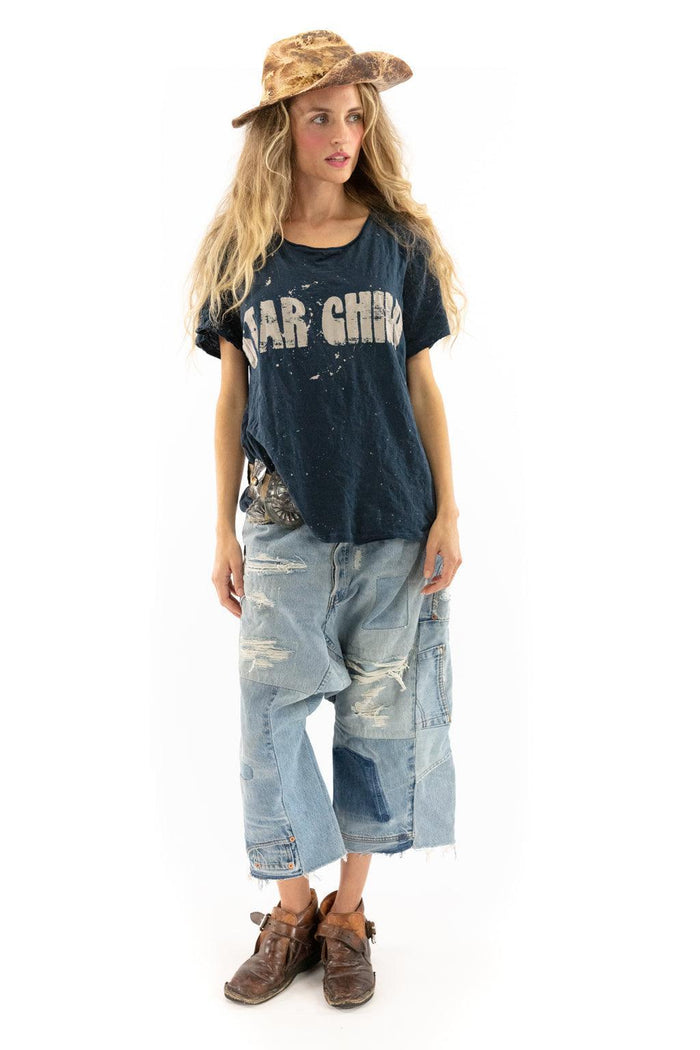 Woman in Magnolia Pearl vintage artisan clothing, wearing distressed jeans, 'Star Child' shirt, rustic hat, and brown boots