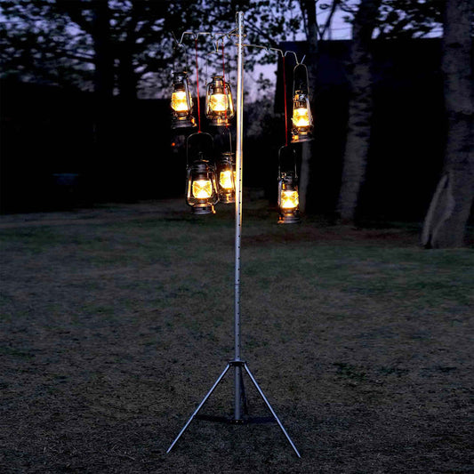 Winnerwell® Lantern & Pipe Stand set up outdoors at night, with lanterns hanging from it, creating a warm ambiance in a natural environment.